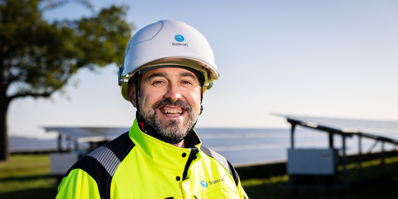 Man wearing safety gear smiling with solar panels in the background