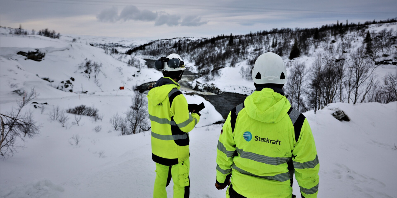 Two colleagues wearing safety gear on top of a hill above the Nesjø dam